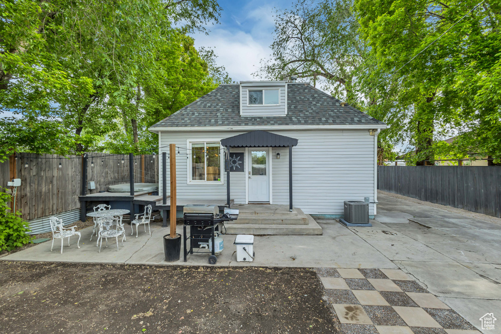 Back of property featuring a fenced backyard, a patio, a shingled roof, an outdoor structure, and central air condition unit