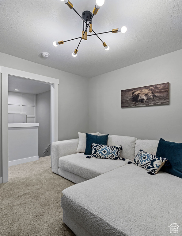 Carpeted bedroom featuring a chandelier, a textured ceiling, and baseboards