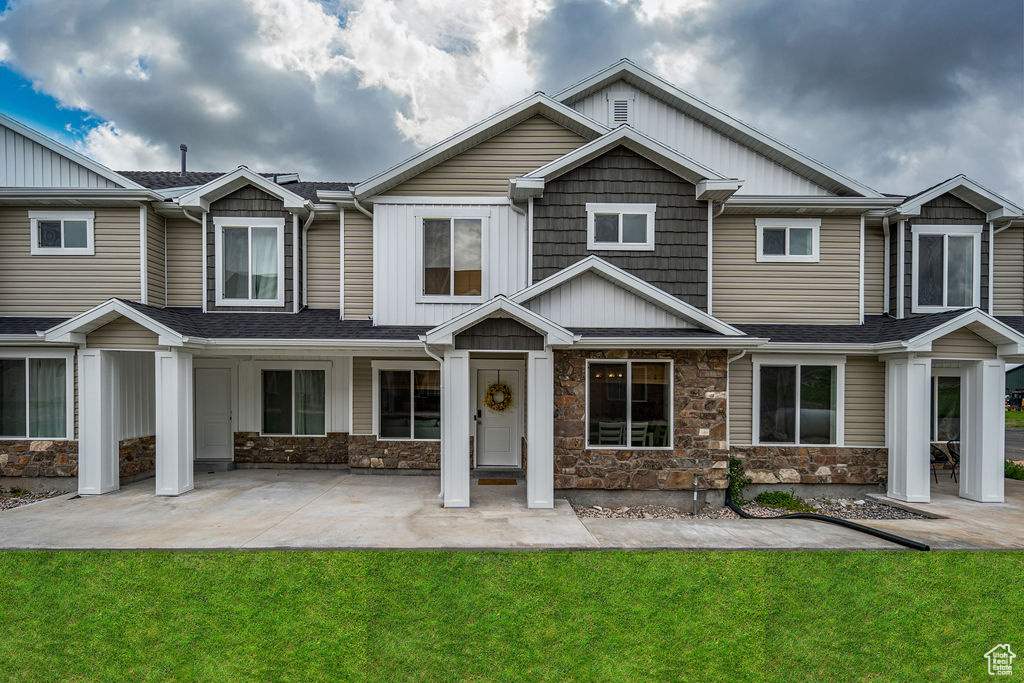 View of front of home with a front yard, stone siding, and board and batten siding