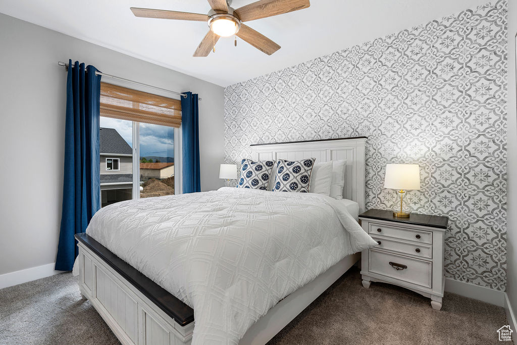 Bedroom with dark colored carpet, wallpapered walls, baseboards, access to exterior, and a ceiling fan