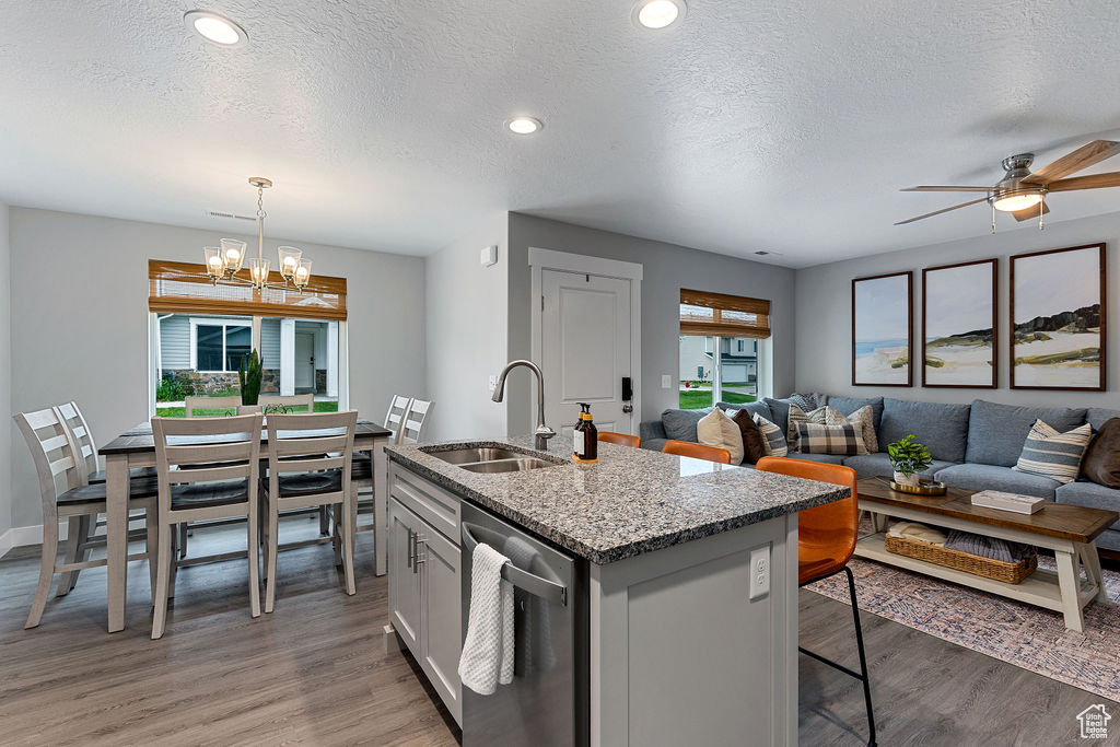 Kitchen with a sink, dishwasher, light wood-style flooring, a textured ceiling, and a chandelier