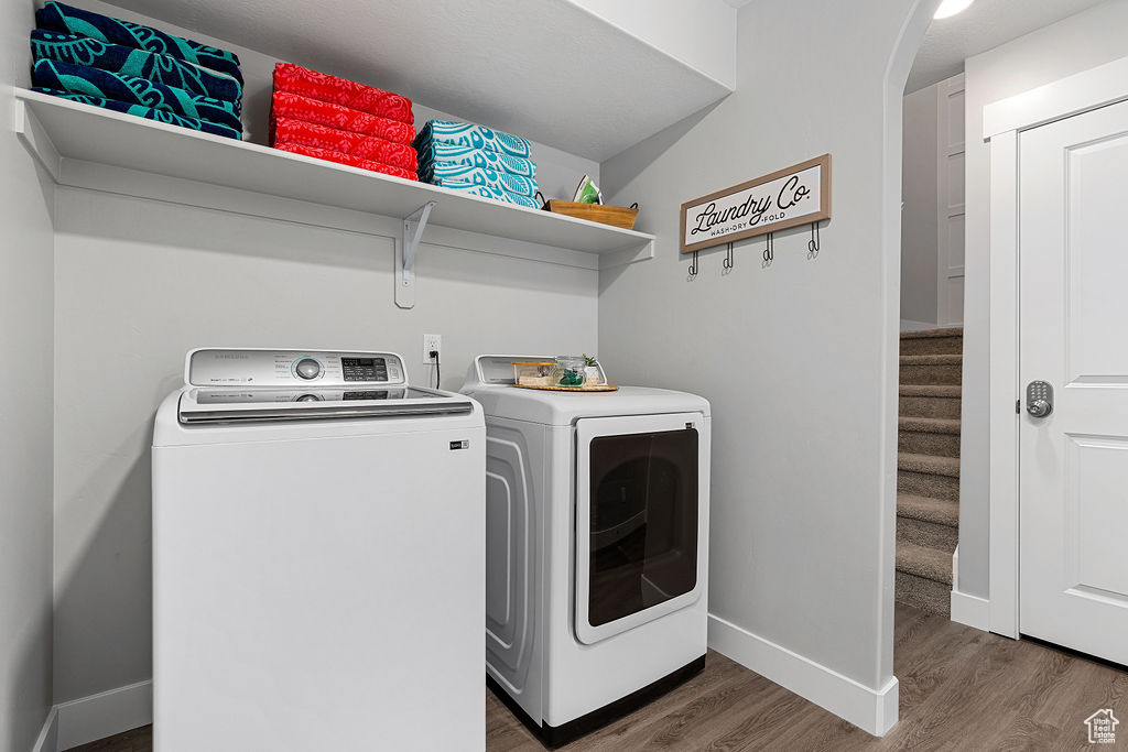 Laundry area featuring washing machine and dryer, wood finished floors, baseboards, and arched walkways