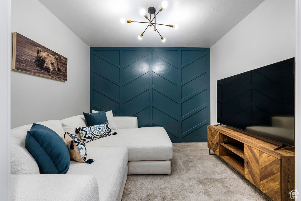 Living area featuring a chandelier, a decorative wall, and light colored carpet