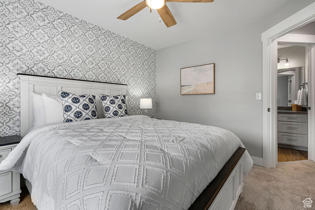 Bedroom featuring wallpapered walls, light carpet, an accent wall, baseboards, and ceiling fan