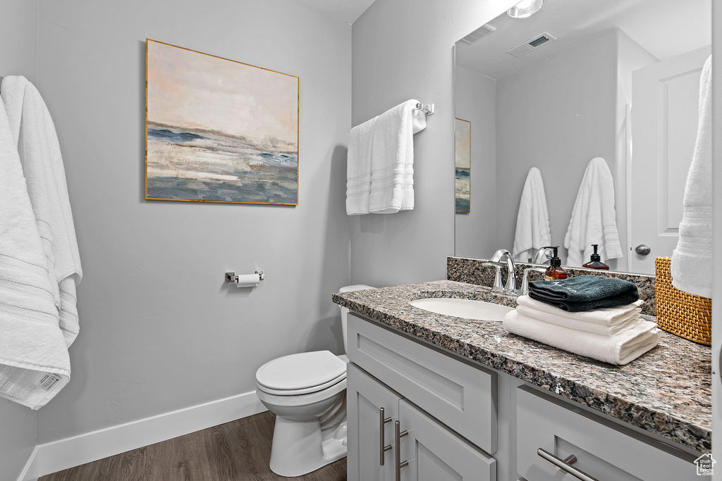 Bathroom with wood finished floors, toilet, vanity, and baseboards