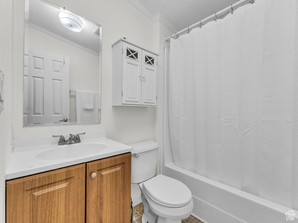 Full bath featuring ornamental molding, toilet, vanity, a textured ceiling, and shower / bath combo with shower curtain