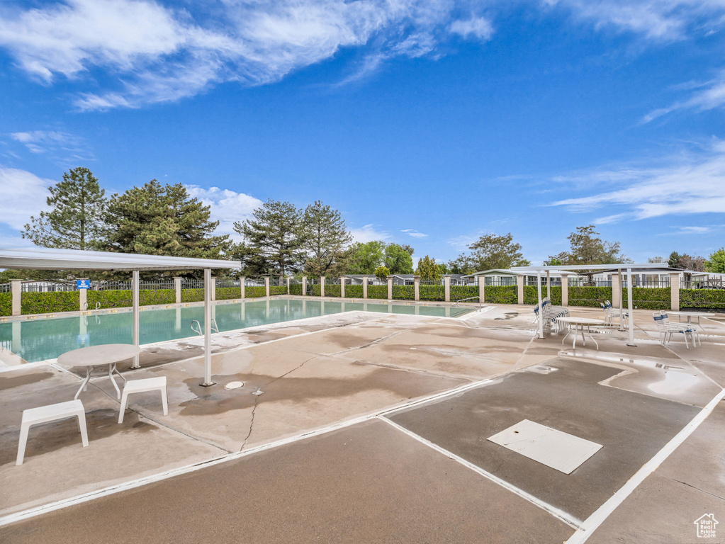 View of car parking featuring a community pool and fence