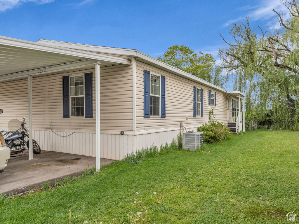 View of property exterior with cooling unit, a yard, and an attached carport