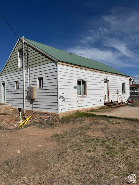 Back of house with metal roof and entry steps