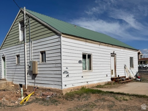 Back of house with metal roof and entry steps