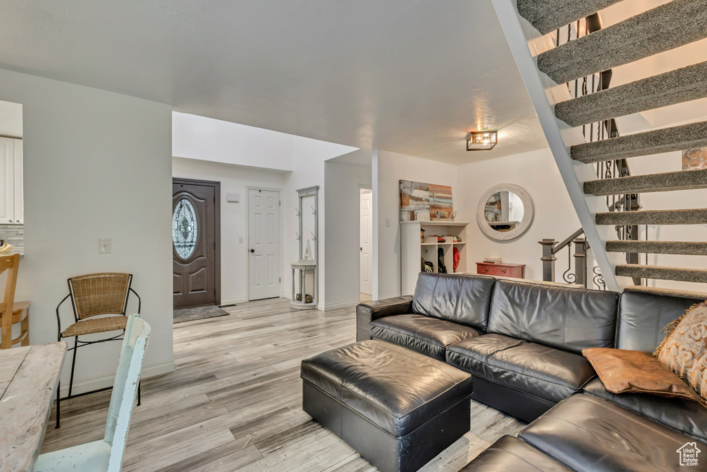 Living room featuring light wood-type flooring, baseboards, and stairs