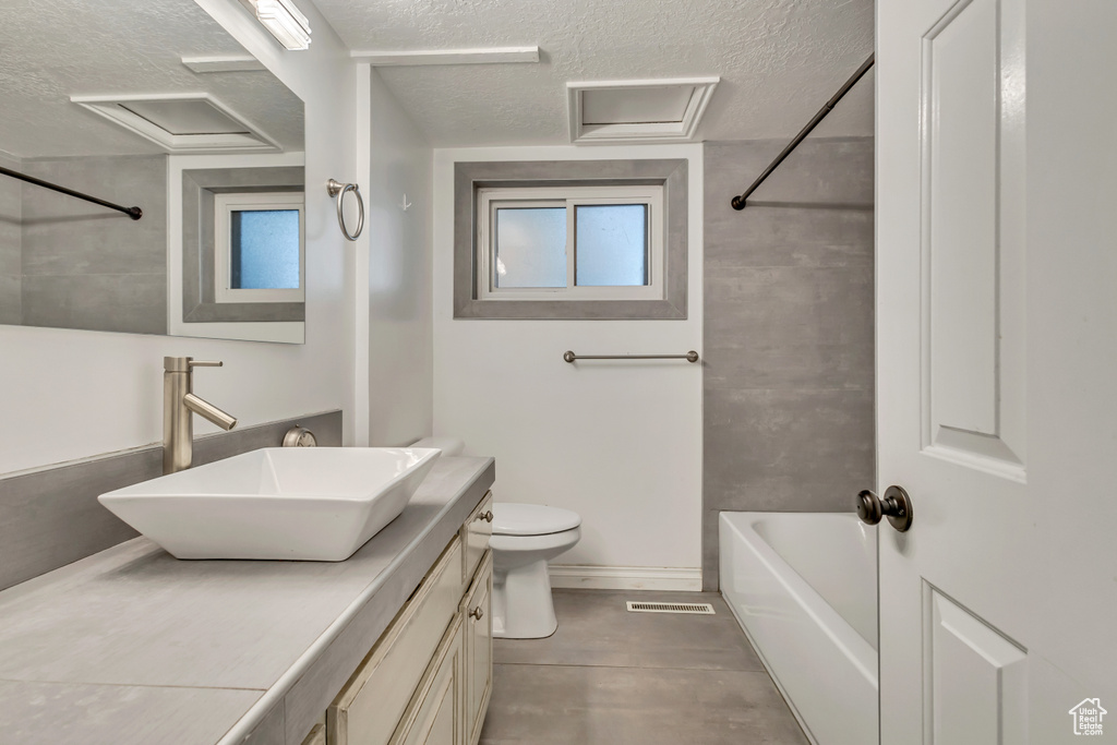 Full bathroom featuring vanity, a textured ceiling, visible vents, and toilet