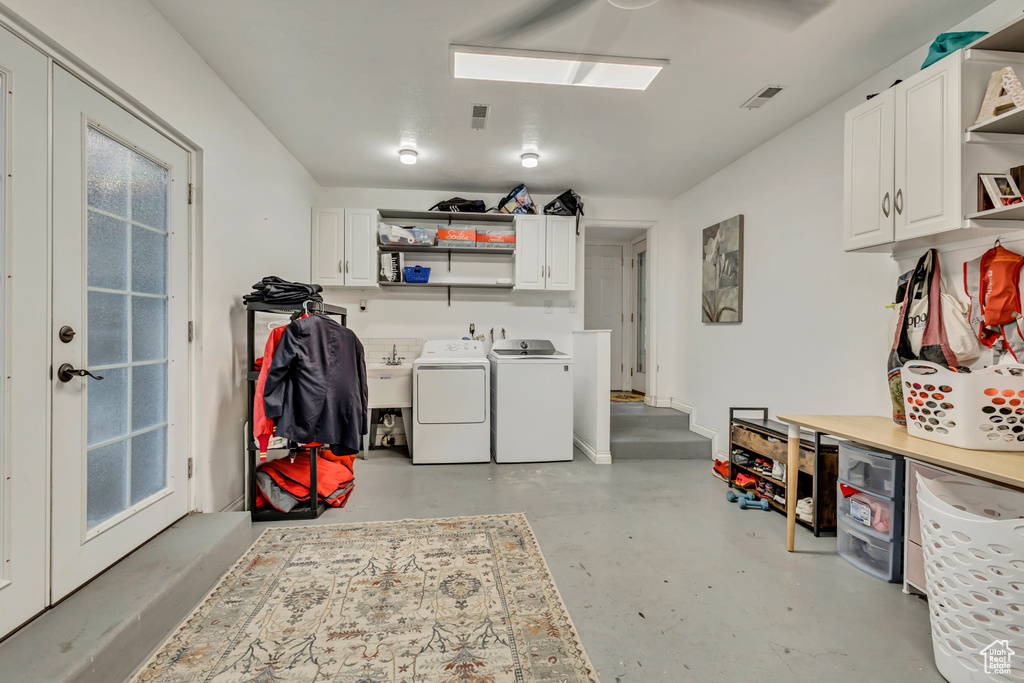 Laundry area with washing machine and clothes dryer, cabinet space, and visible vents