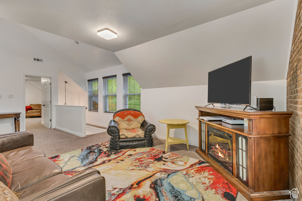Carpeted living room with baseboards, visible vents, and vaulted ceiling
