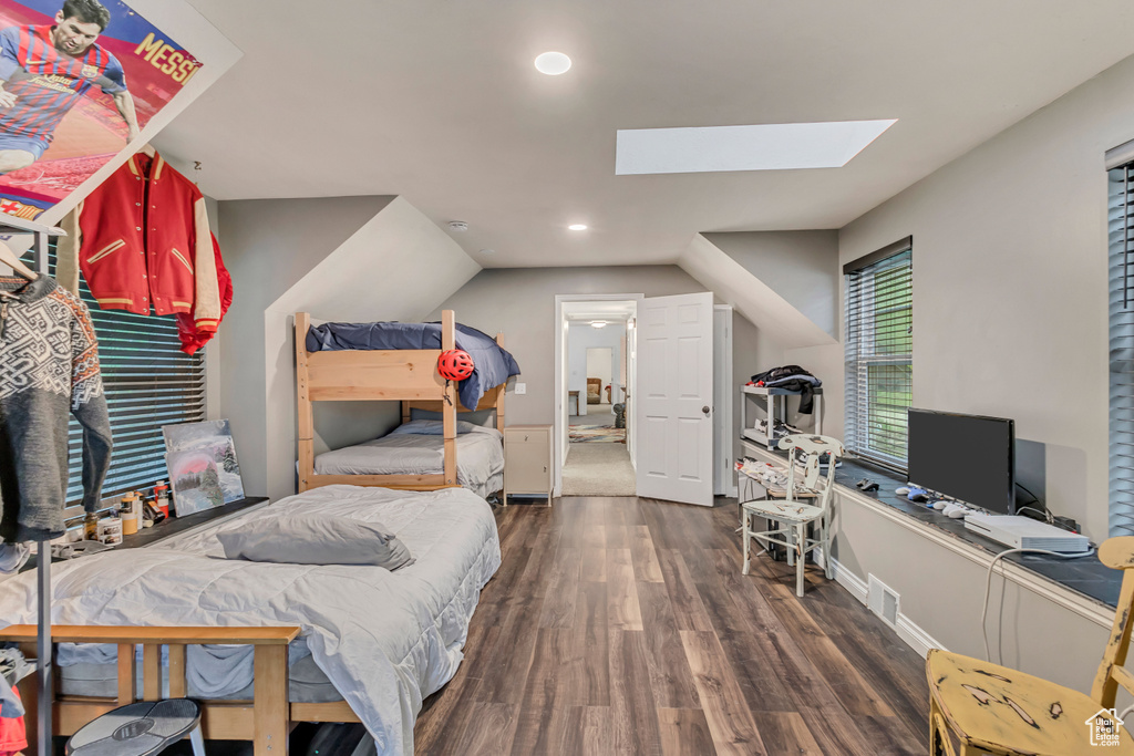 Bedroom featuring wood finished floors, vaulted ceiling with skylight, visible vents, baseboards, and recessed lighting
