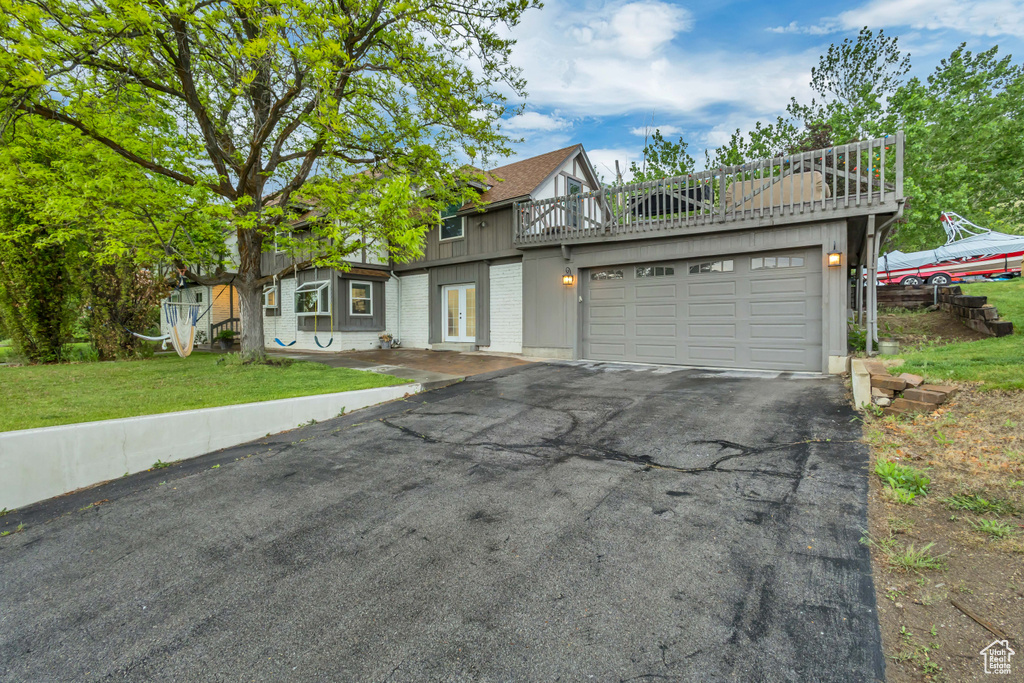 Tudor home featuring a garage, board and batten siding, a front yard, brick siding, and driveway