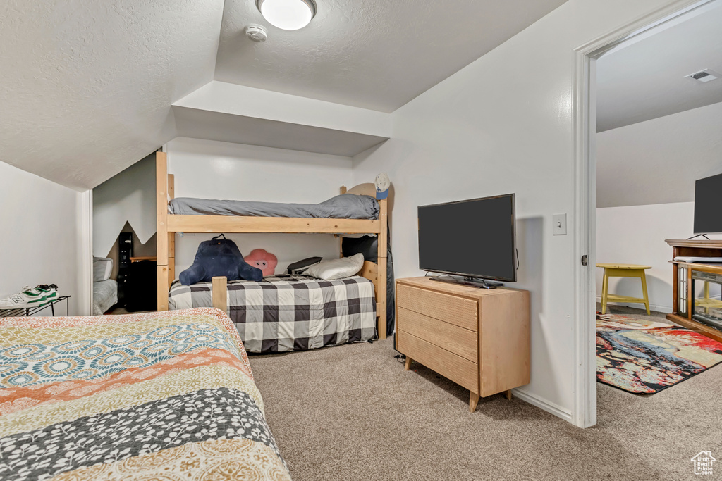 Bedroom with lofted ceiling, visible vents, and carpet