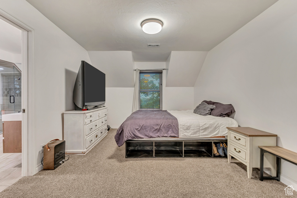 Carpeted bedroom featuring connected bathroom and visible vents