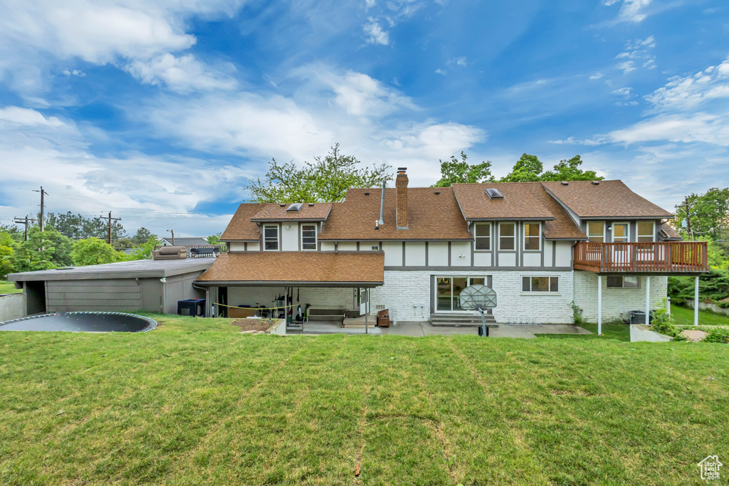 Rear view of house with a yard, a shingled roof, a patio, and a chimney