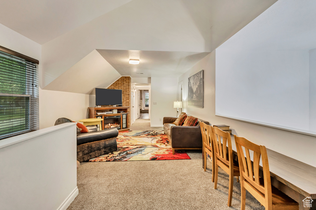 Living area with carpet, lofted ceiling, and a brick fireplace