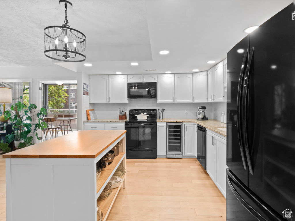 Kitchen featuring black appliances, wine cooler, recessed lighting, white cabinetry, and light wood-style flooring