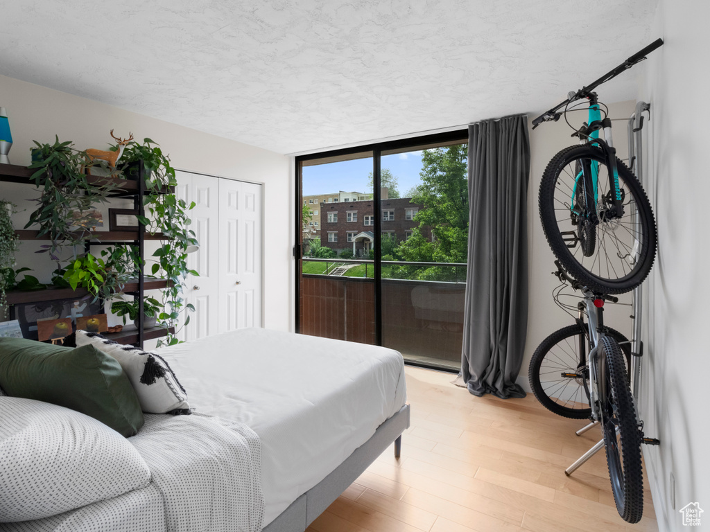 Bedroom with a textured ceiling, light wood-style flooring, access to exterior, a closet, and floor to ceiling windows