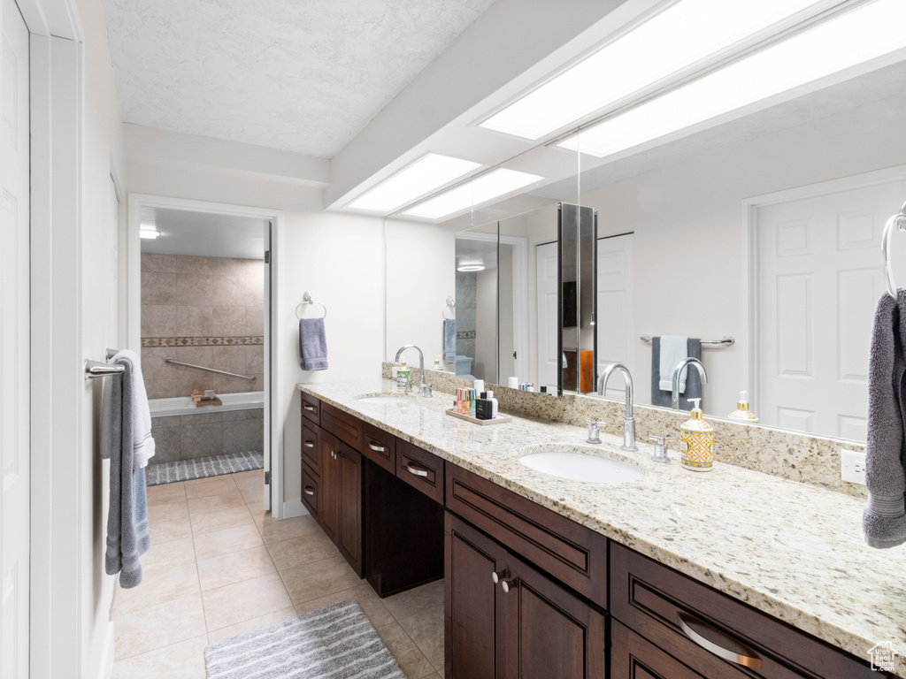 Bathroom with tile patterned flooring, double vanity, tiled bath, and a shower