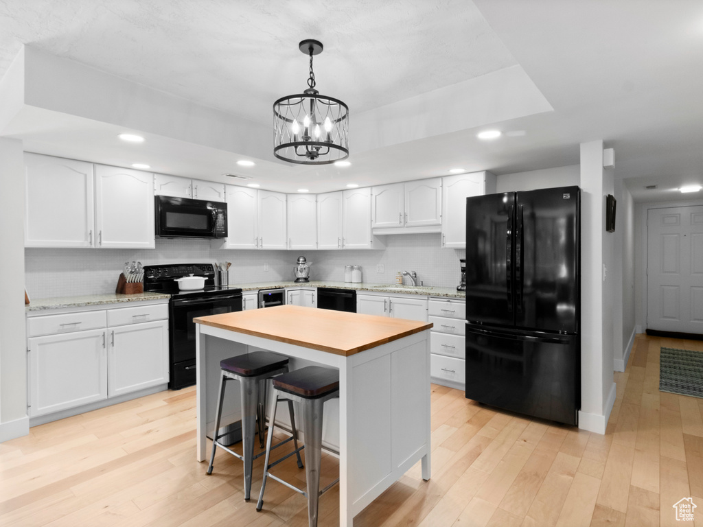 Kitchen featuring black appliances, light countertops, white cabinetry, recessed lighting, and light wood-style floors