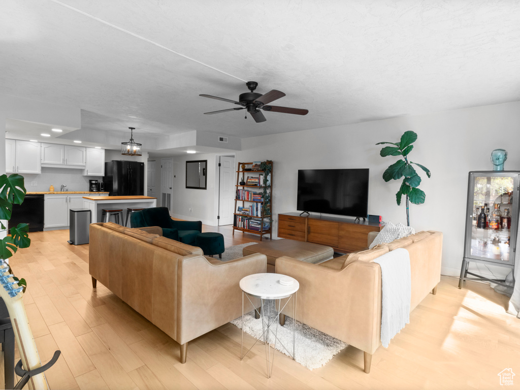 Living room with light wood finished floors, a ceiling fan, and recessed lighting