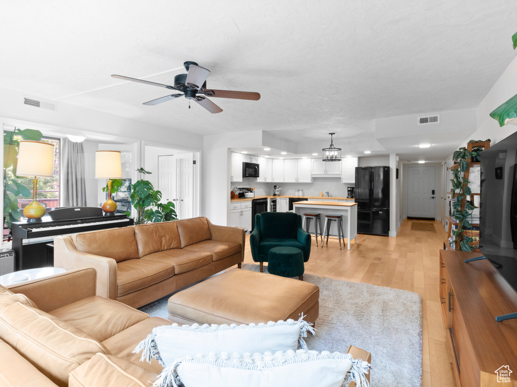 Living area with a ceiling fan, light wood-type flooring, and recessed lighting