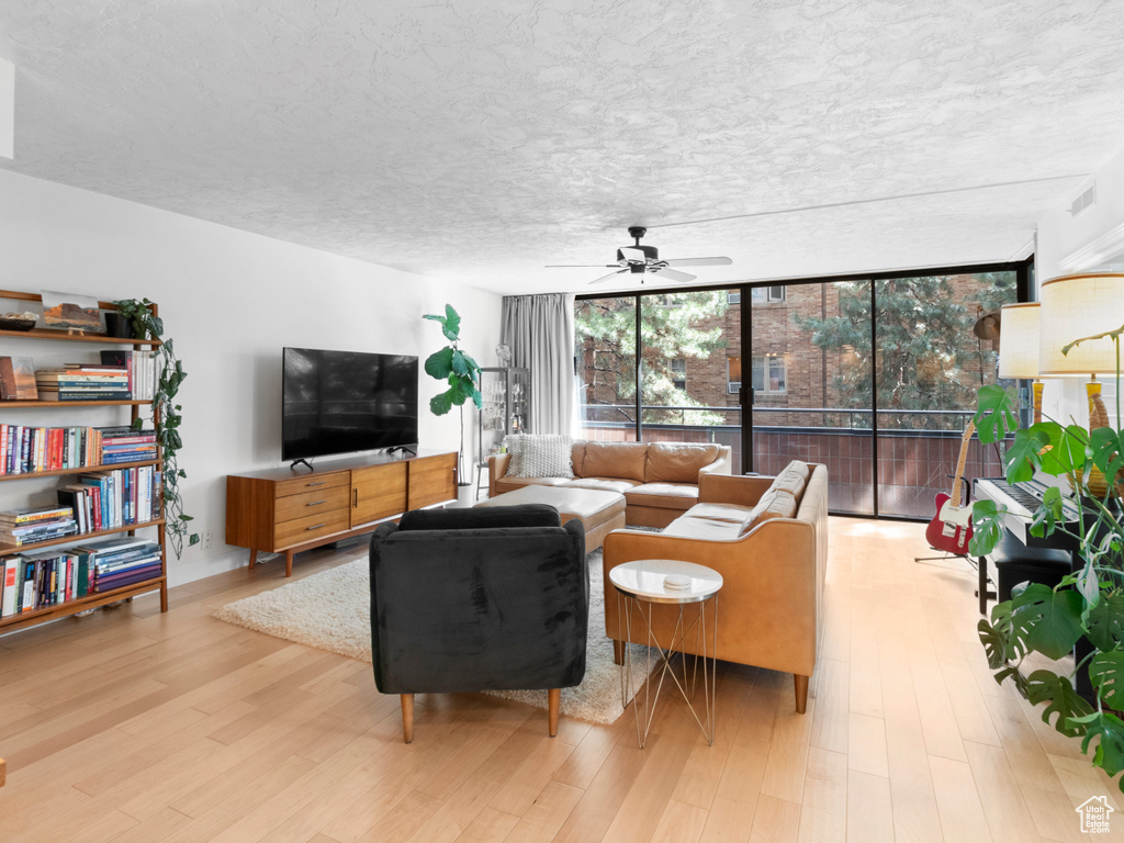 Living room featuring a wall of windows, ceiling fan, and wood finished floors