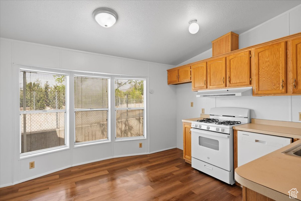 Kitchen with white appliances, under cabinet range hood, light countertops, lofted ceiling, and dark wood-style flooring
