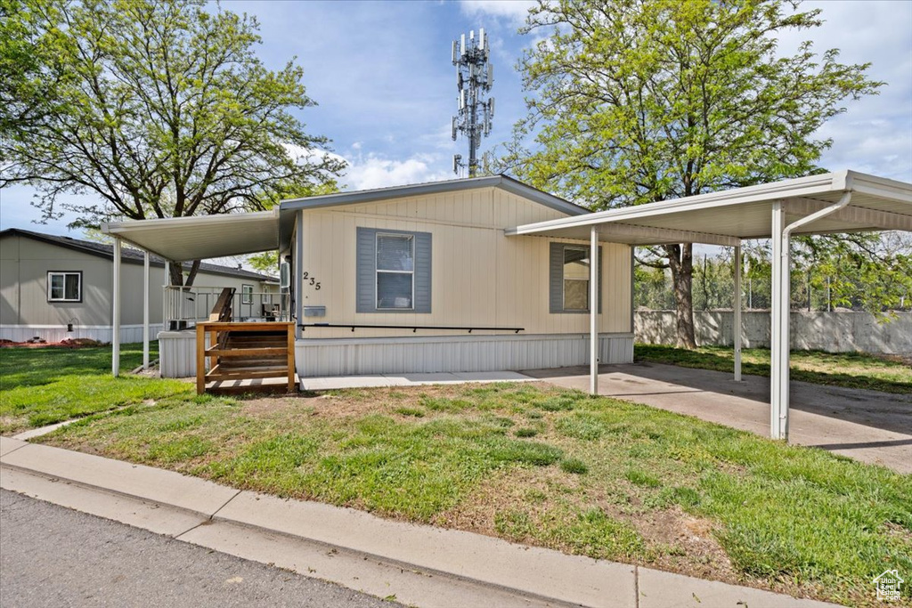 Manufactured / mobile home with a front lawn and a carport