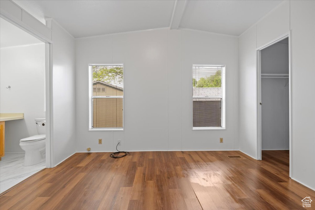 Unfurnished bedroom with wood finished floors, a walk in closet, a closet, and connected bathroom