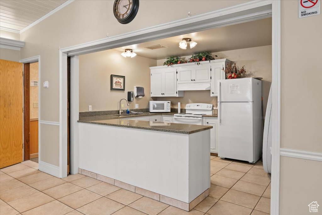Kitchen with white appliances, ornamental molding, a sink, light tile patterned floors, and white cabinetry
