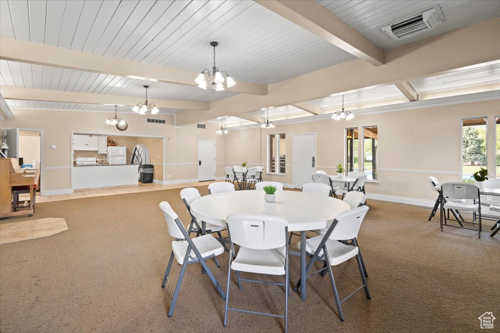 Carpeted dining area with a chandelier, beam ceiling, and baseboards