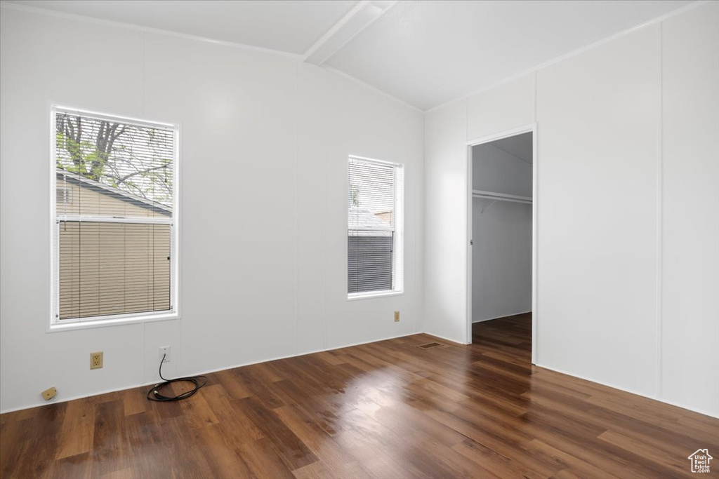 Unfurnished bedroom featuring vaulted ceiling, wood finished floors, a walk in closet, and a closet