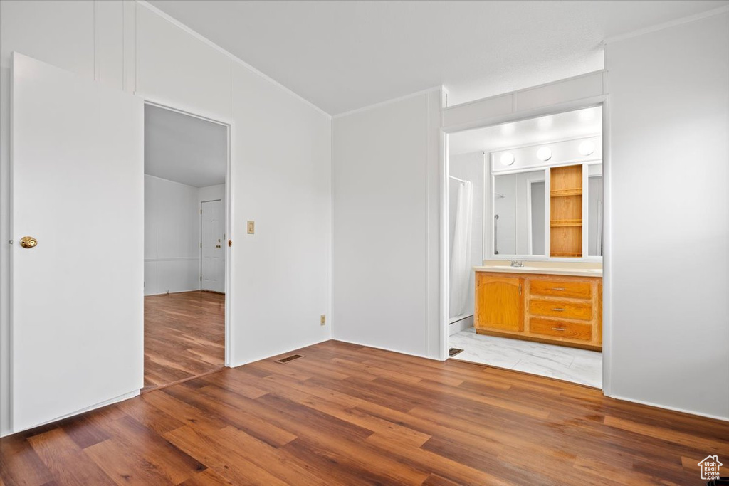 Unfurnished bedroom featuring light wood-style floors and ensuite bathroom