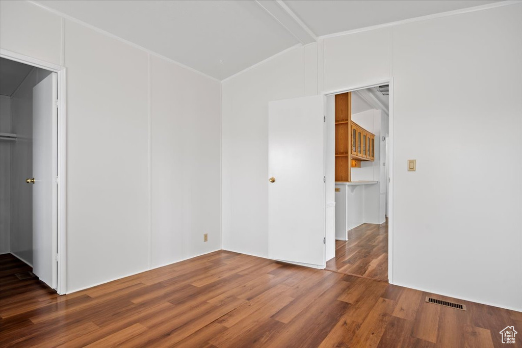 Empty room with wood finished floors and lofted ceiling