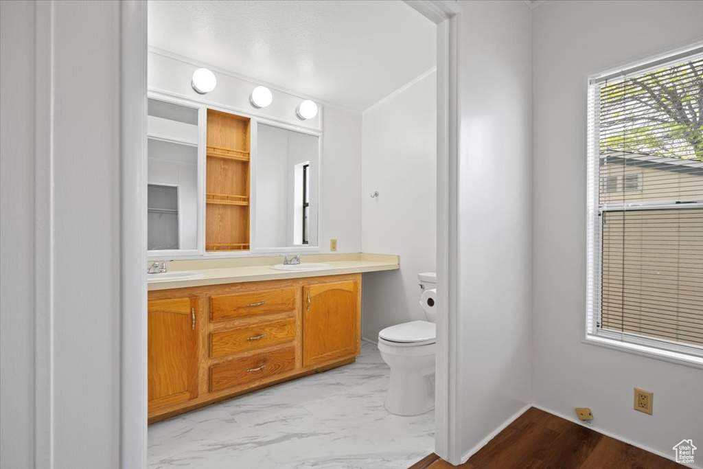 Bathroom with toilet, double vanity, and marble finish floors