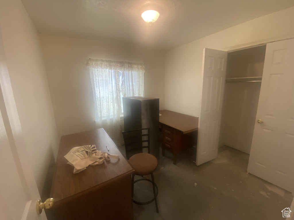 Bedroom with concrete floors, a closet, and a desk