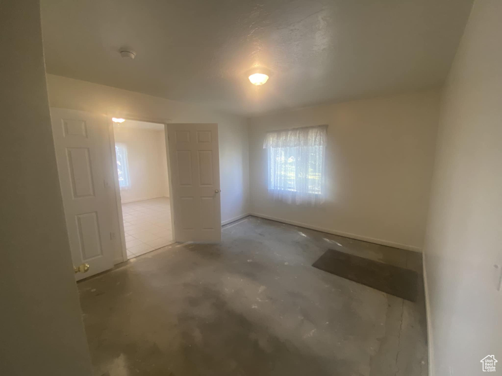 Unfurnished bedroom featuring multiple windows and concrete flooring
