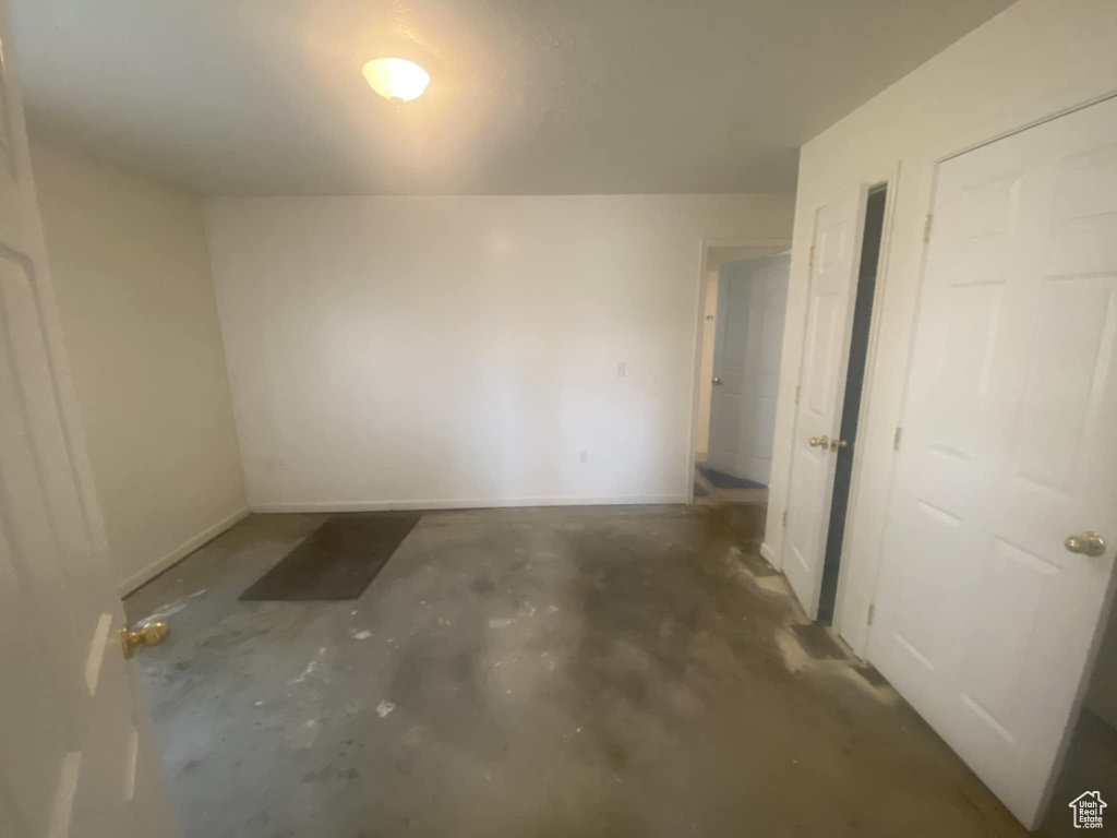 Unfurnished room with unfinished concrete floors and baseboards