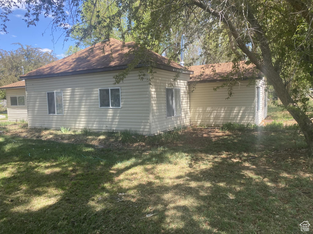 View of home\\\'s exterior with a yard and roof with shingles