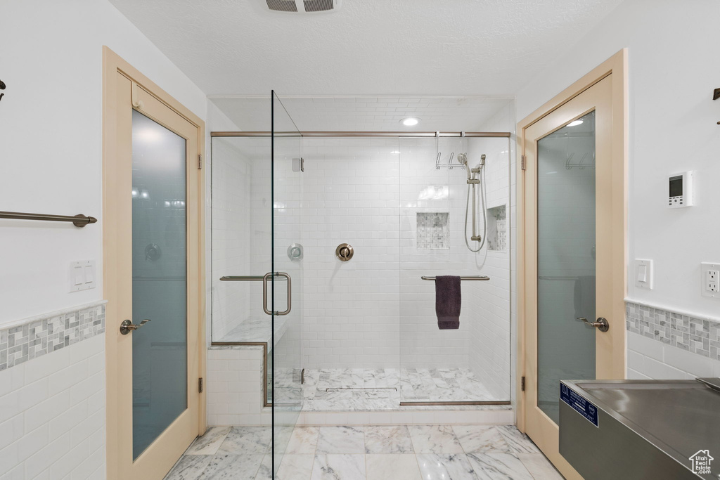 Bathroom featuring a stall shower, tile walls, a wainscoted wall, and marble finish floor