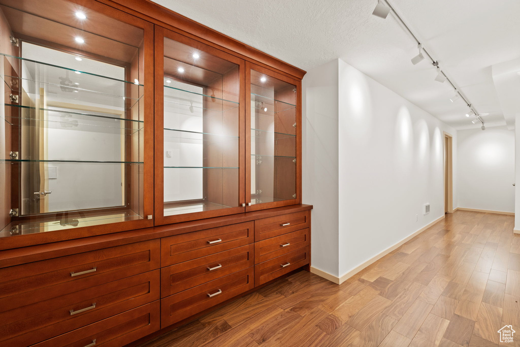 Hall featuring baseboards, track lighting, and wood finished floors