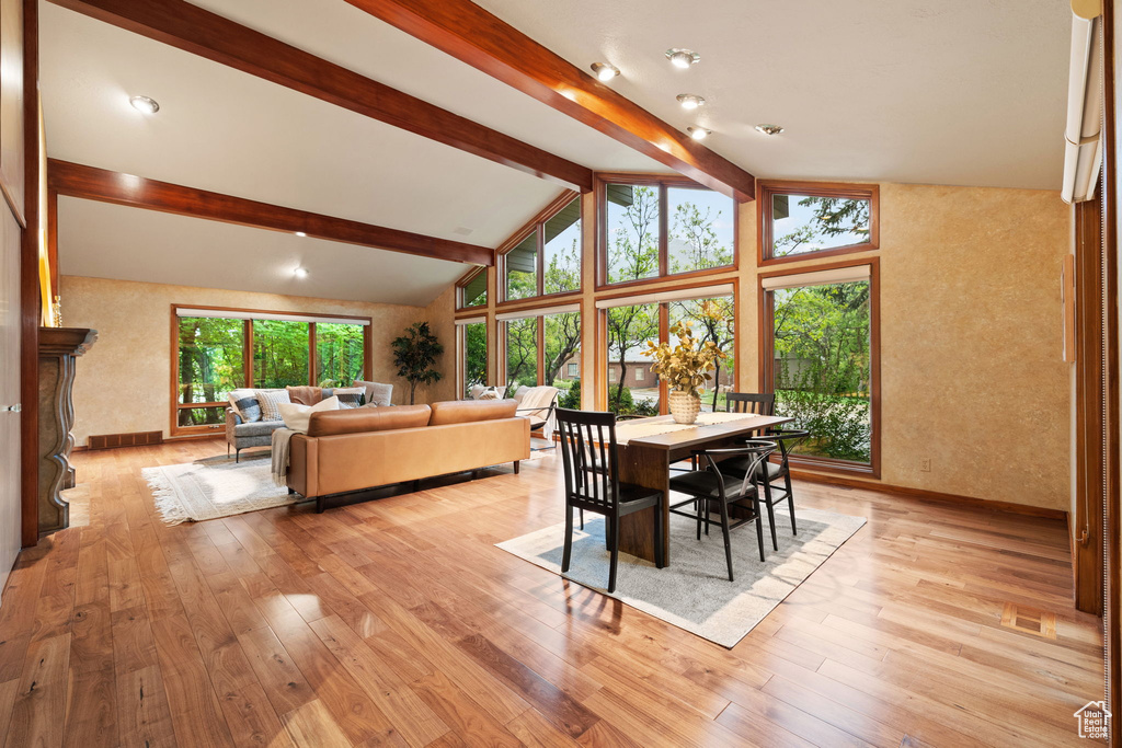 Dining room with beam ceiling, baseboards, light wood-style flooring, and high vaulted ceiling
