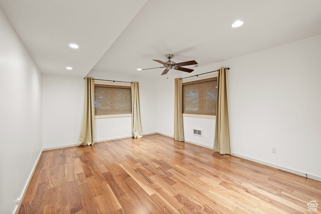 Empty room with visible vents, light wood-style flooring, ceiling fan, and recessed lighting