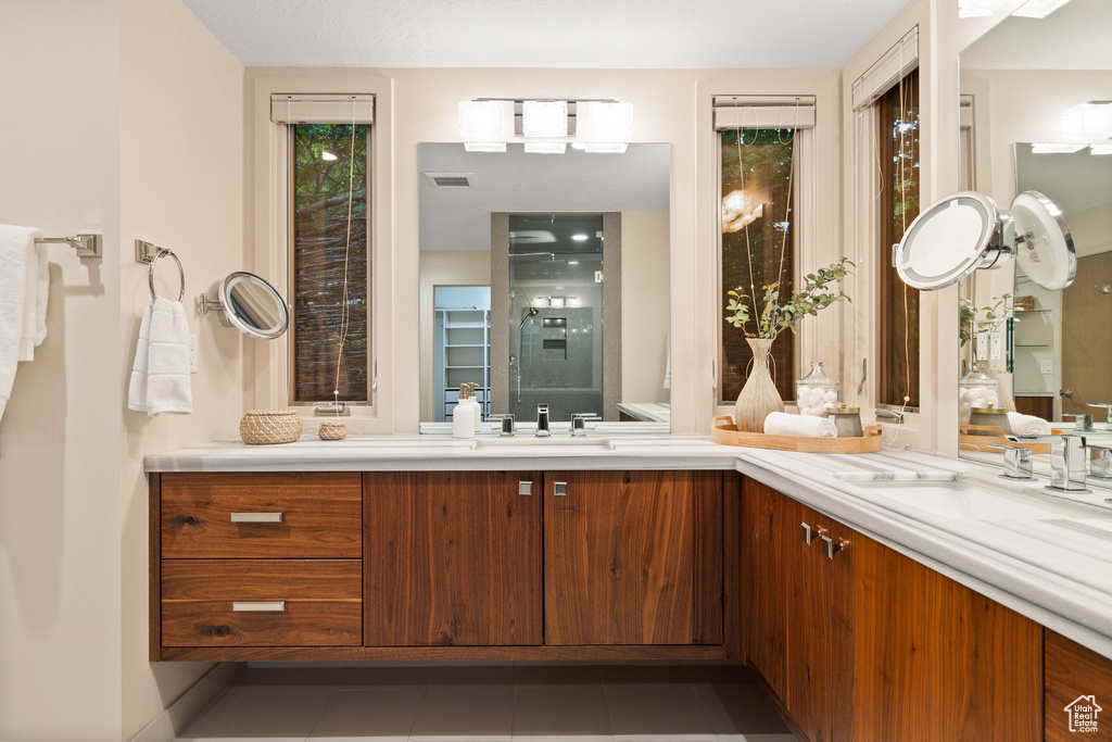Full bath featuring double vanity, visible vents, tile patterned flooring, and a sink
