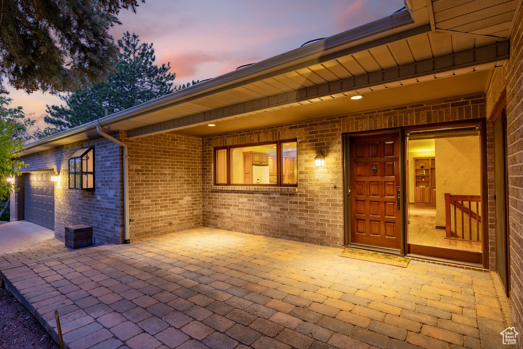 Patio terrace at dusk featuring driveway and a garage